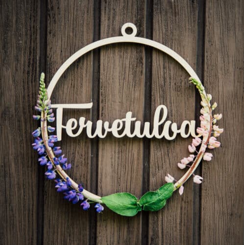 Vanerinen ovikranssi tervetuloa tekstillä ruskeaa seinää vasten ja koristeltuna lupiineilla.