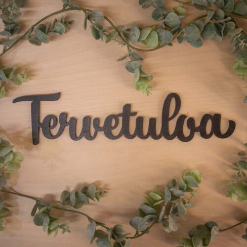 Puinen mustanvärinen Tervetuloa kyltti ulko-oveen.