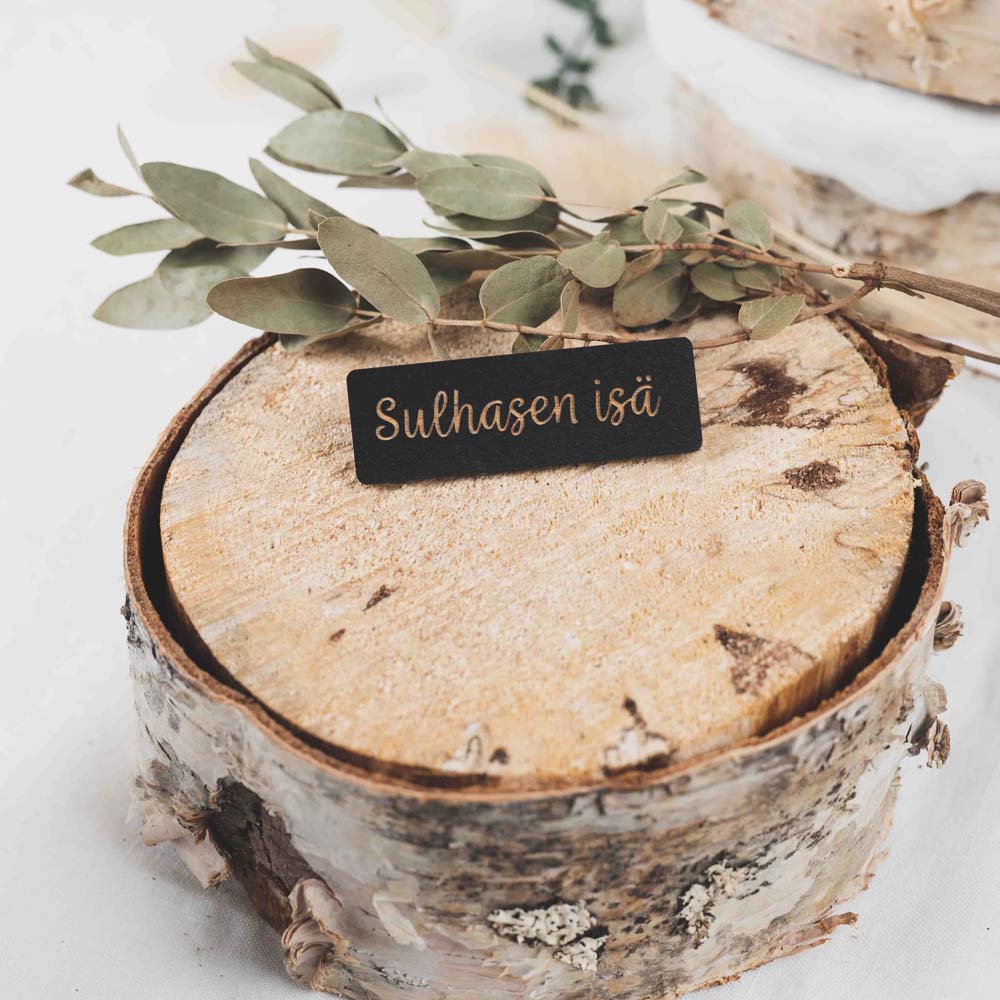 Musta puinen paikkakyltti tekstillä sulhasen isä.