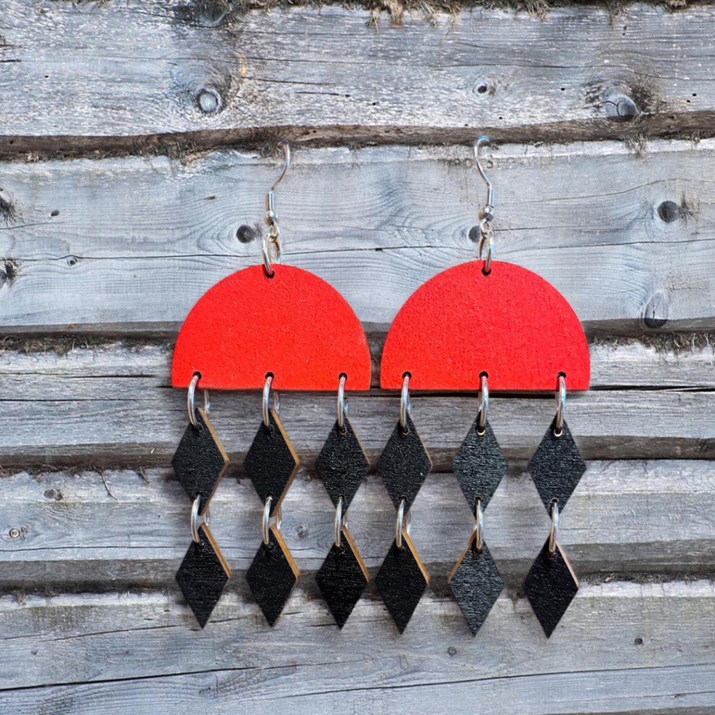 Korvakoru jossa punainen puoliympyrä ja mustat roikkuvat salmiakit